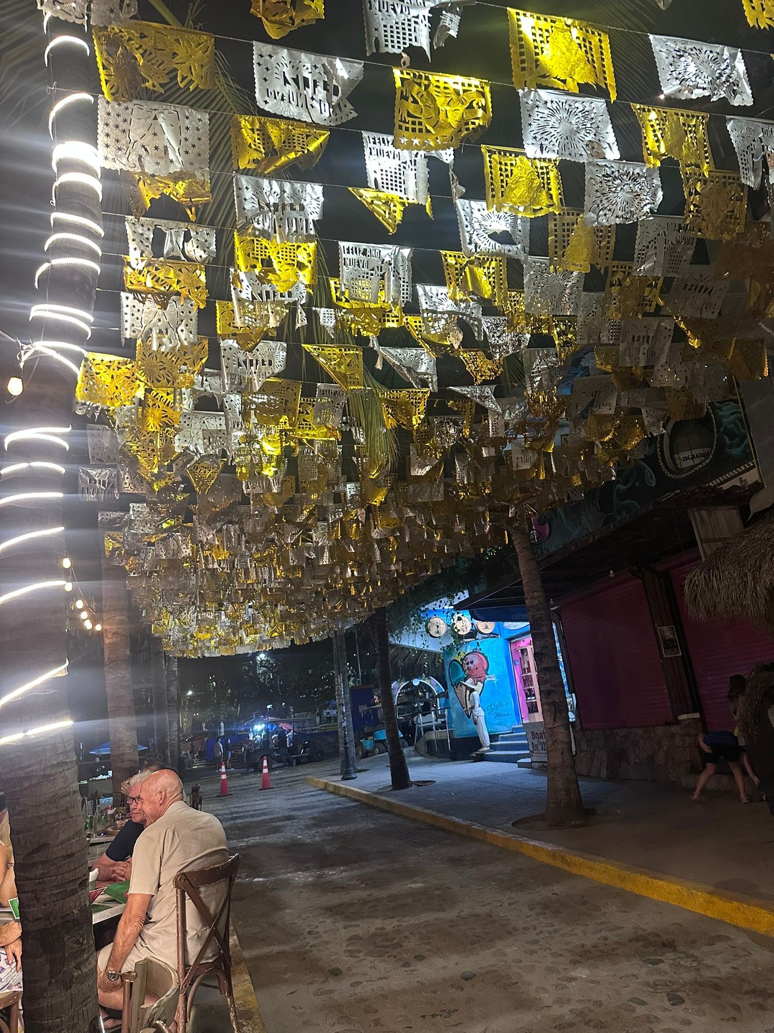 A man in a wheelchair is sitting under a canopy of flags.