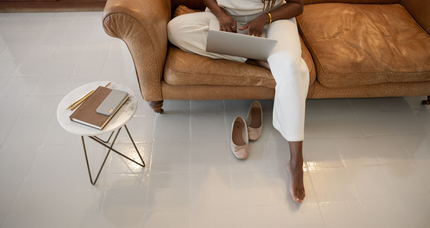 A woman is sitting on a couch using a laptop computer.