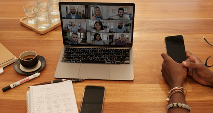 A person is sitting at a table with a laptop and a cell phone.