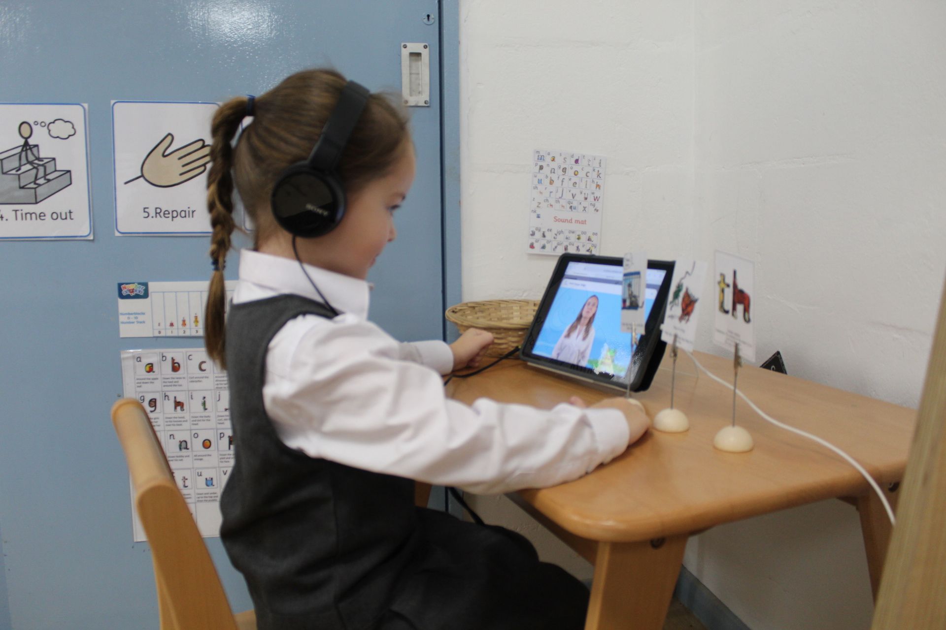 Children in a classroom. One raises his hand, others watch.