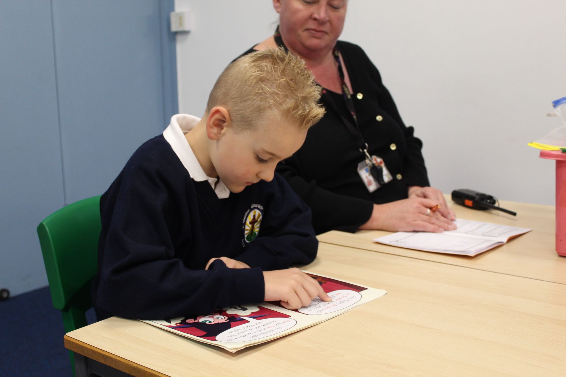 Children in school uniforms writing at desks in a classroom.