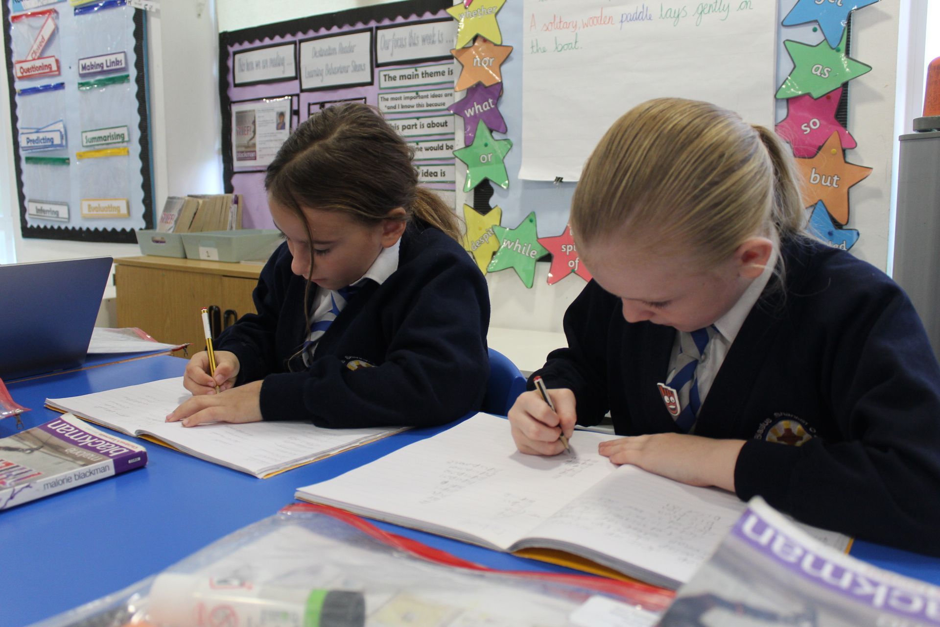 Children playing hopscotch on a paved area outside a school building.
