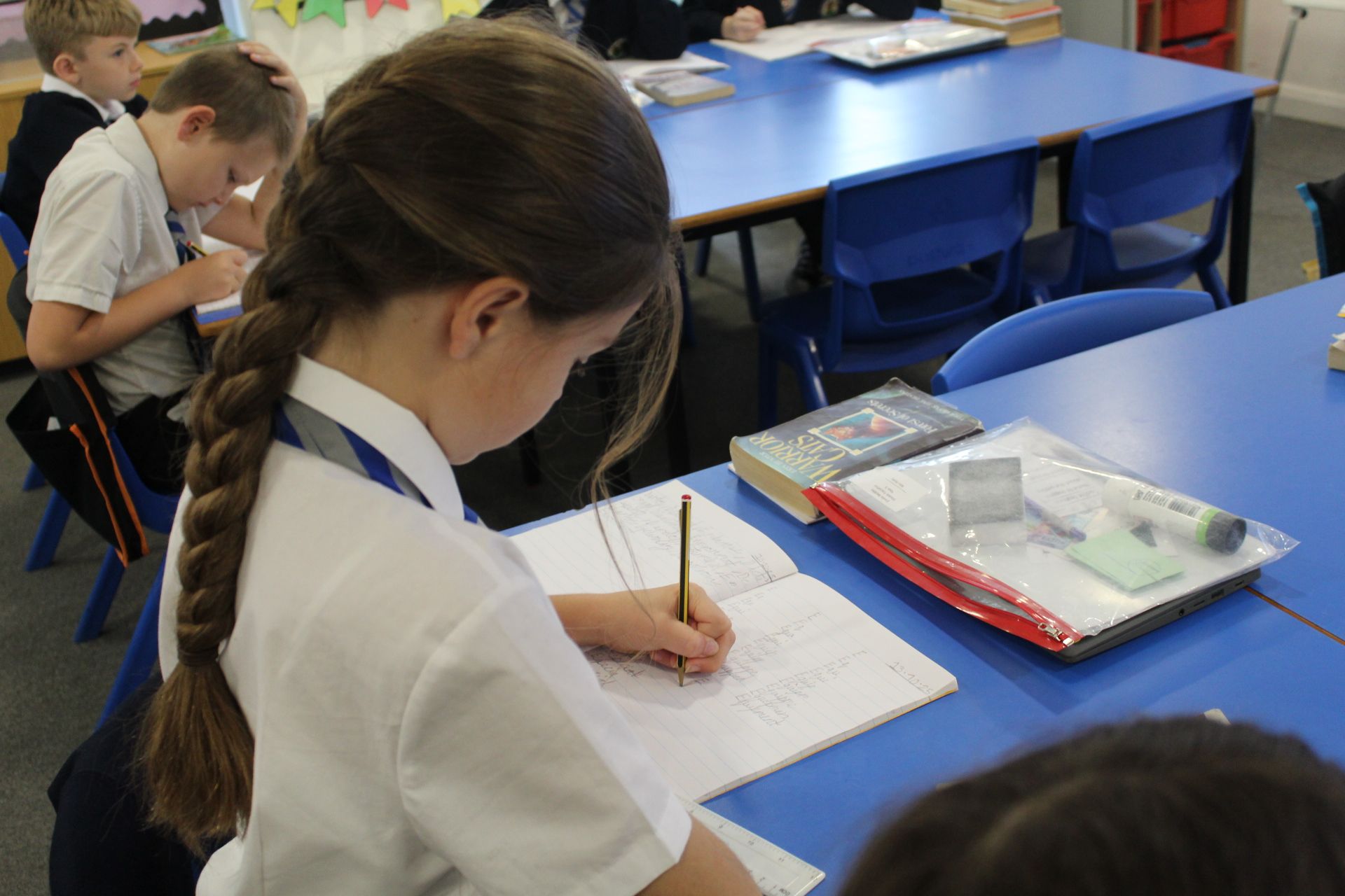Children playing in a wooden car made from repurposed spools. Two boys climb on, while others sit inside. Outdoors.