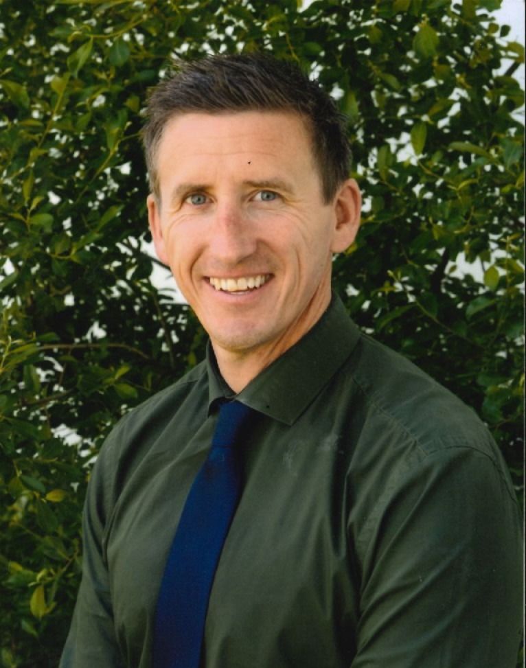 Man in a suit smiles, blue gradient background.