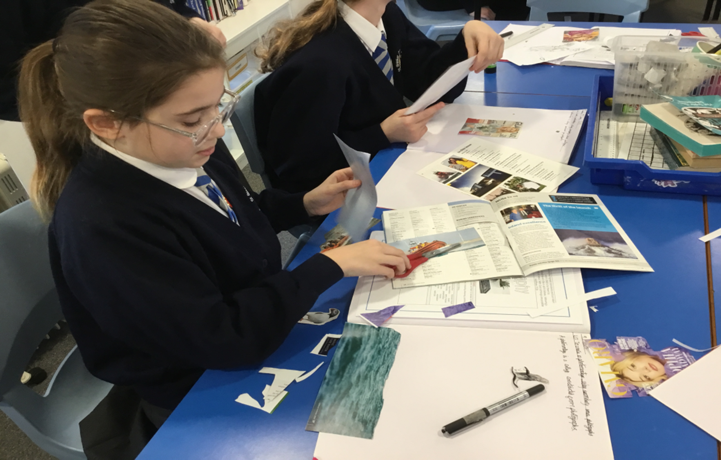 A group of children are sitting at a table looking at papers