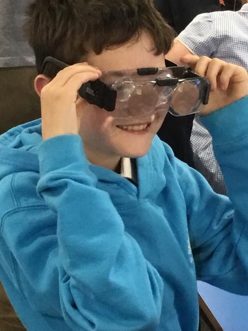A young boy wearing a blue sweatshirt and clear goggles