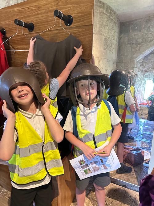 A group of children wearing safety vests and helmets are standing next to each other.