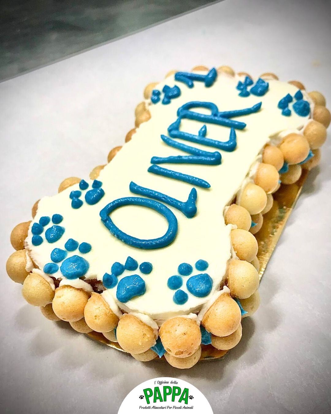 Torta a forma di osso di cane con impronte di zampe blu e la scritta 