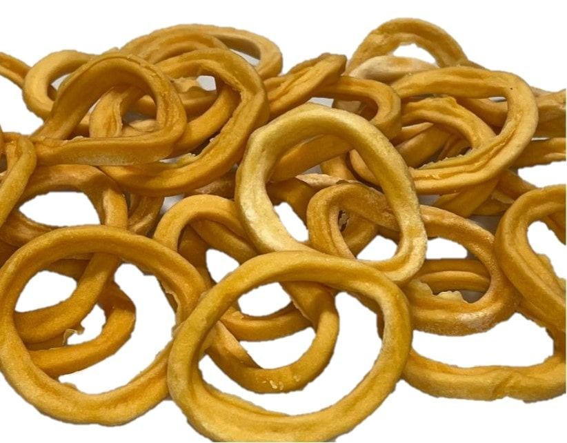 Un mucchio di anelli di cipolla dorati, strettamente arricciati, ammucchiati insieme, alcuni sovrapposti.
