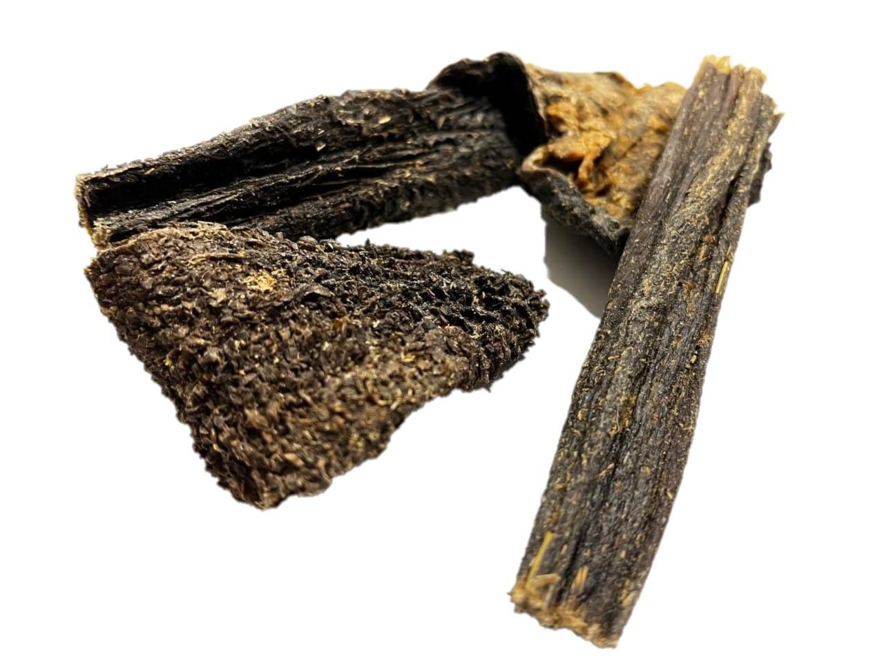 Pezzi di trippa essiccati di colore scuro, dalla consistenza ruvida e dalla superficie su sfondo bianco.