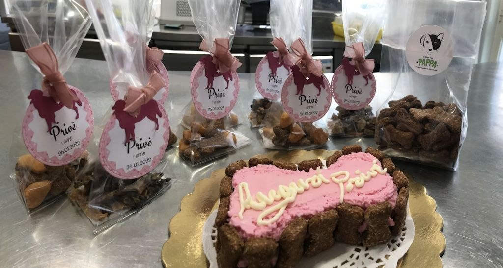 Prodotti da forno confezionati con decorazioni in nastro rosa e una torta con glassa rosa.