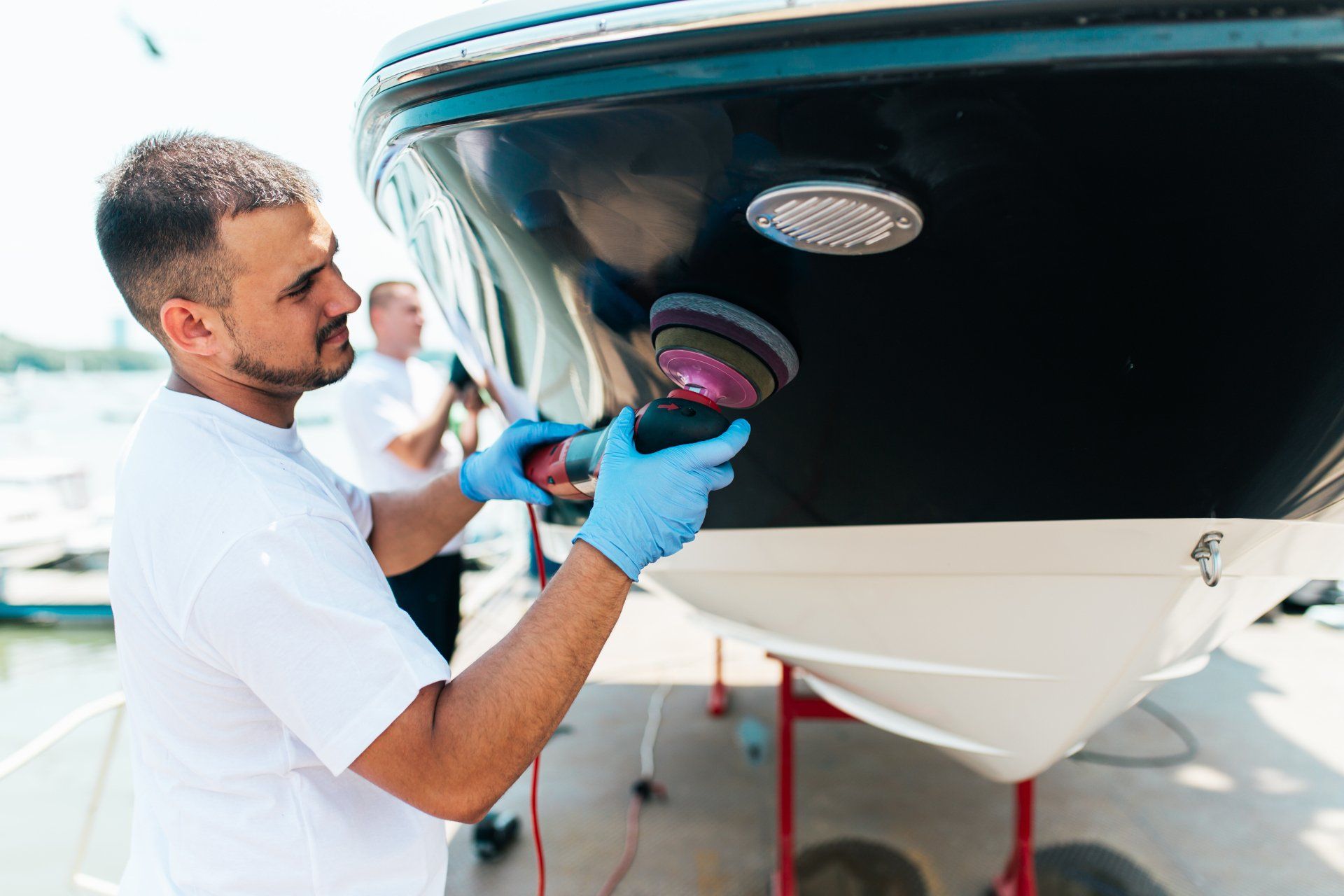 Two men detailing the underside of a boat