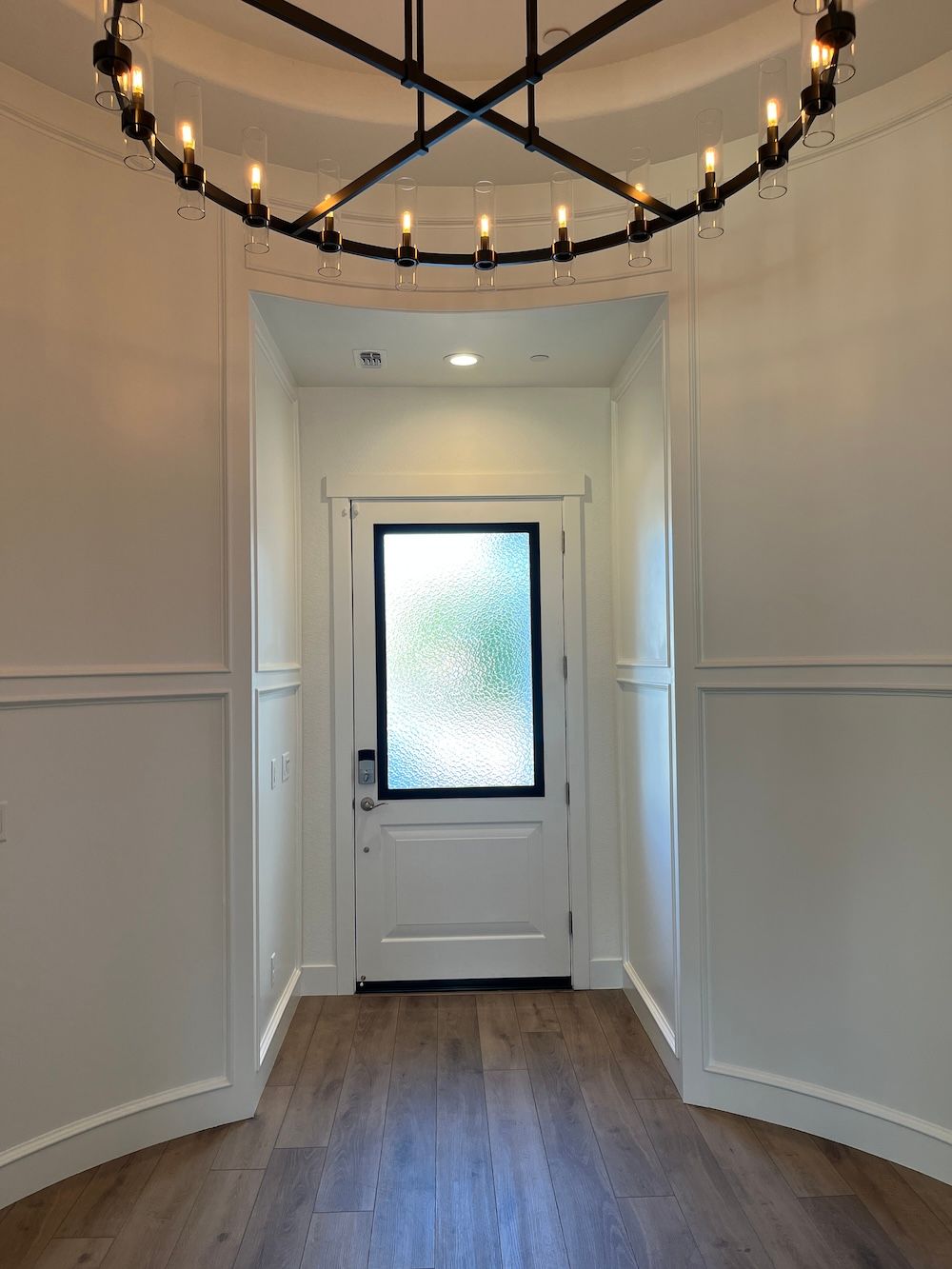 A hallway with a door and a chandelier hanging from the ceiling