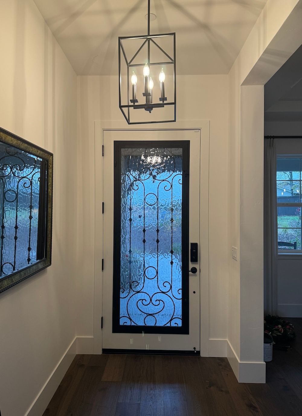 A hallway with a door and a chandelier hanging from the ceiling.