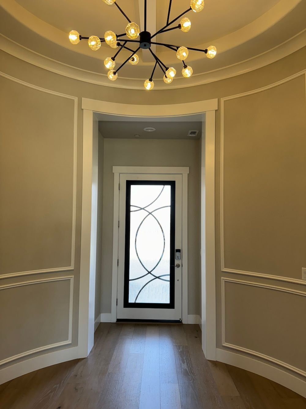 A hallway with a door and a chandelier hanging from the ceiling