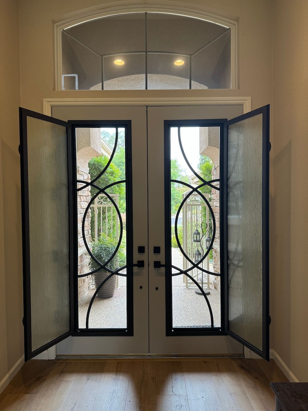 A door with a wrought iron design is open to a balcony