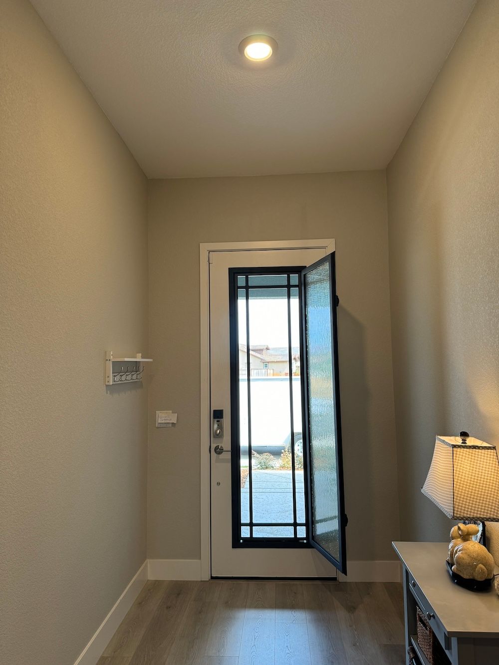 A hallway with a door open and a lamp on a table