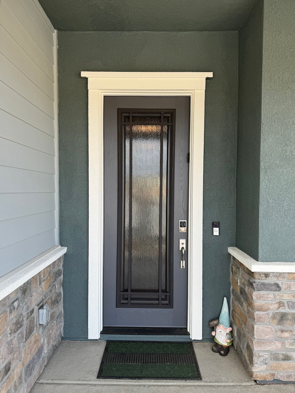 The front door of a house with a gnome on the porch.