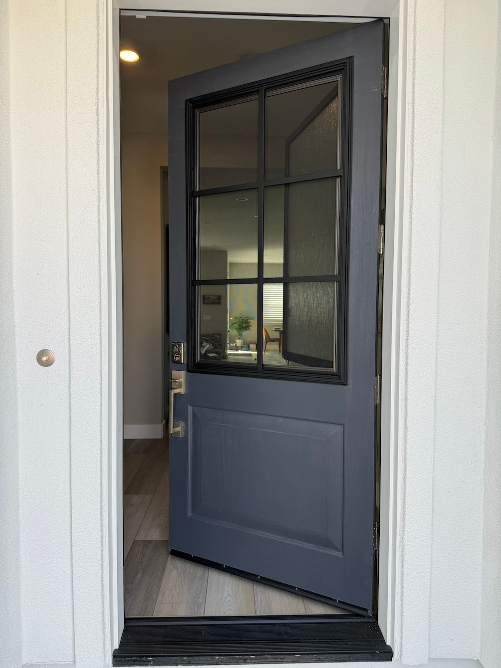 A blue door with a glass window is open to a room.