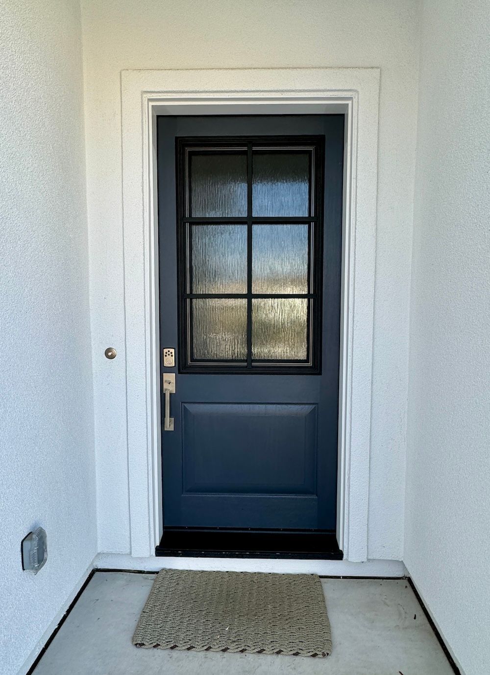 A blue door with a white trim and a doormat in front of it