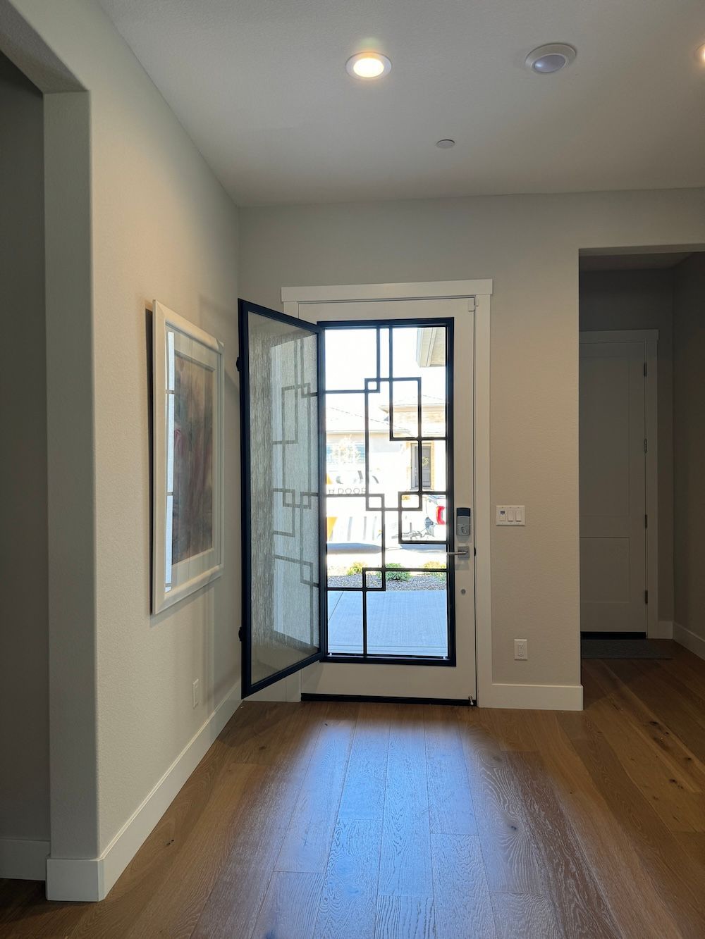 A hallway with a door open and a picture on the wall