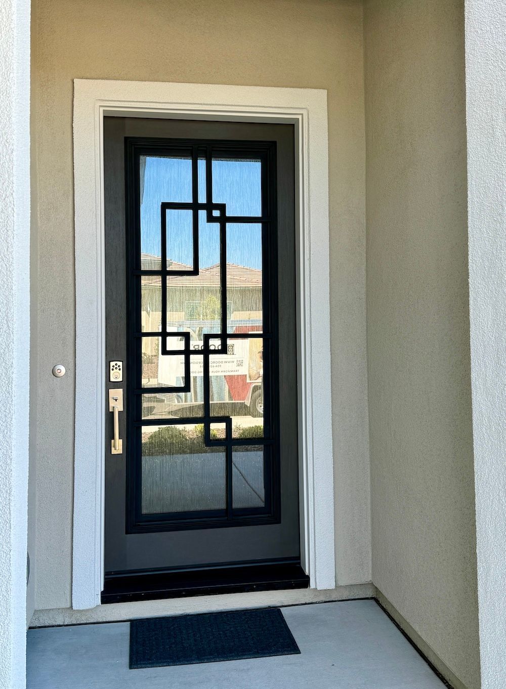 The front door of a house with a black door and a black mat.