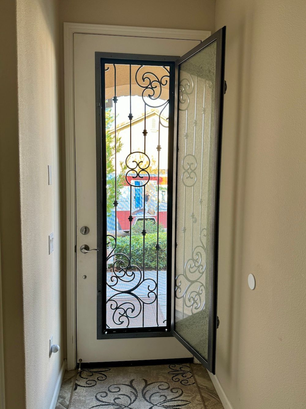 A door with a wrought iron design on it is open in a hallway.
