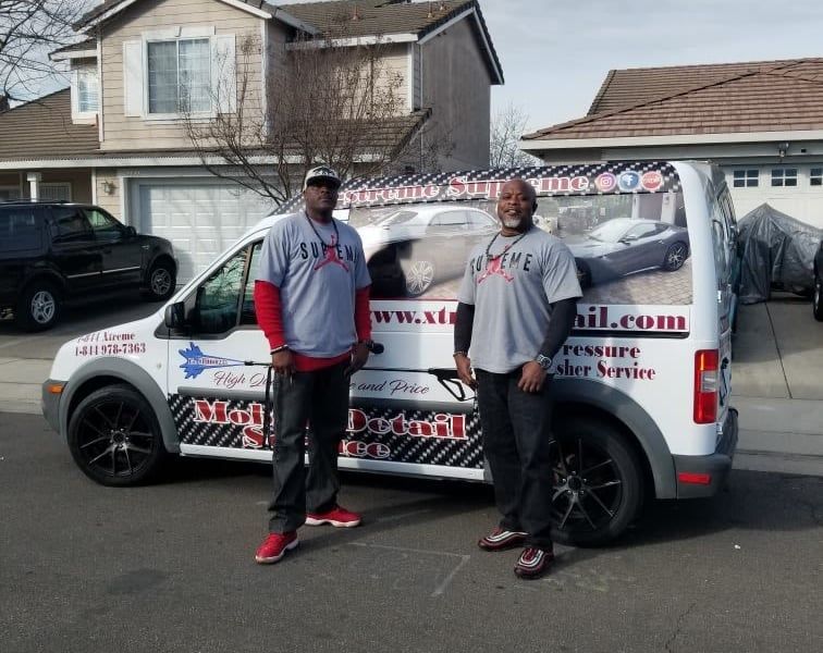 Two men standing in front of a white van that says www.sd.com