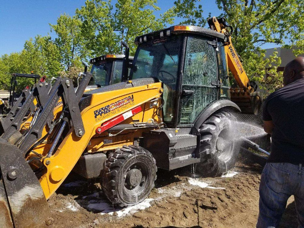 a man is washing a bulldozer in the dirt