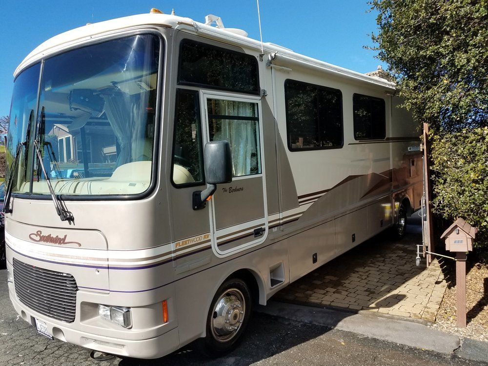 a large white rv is parked on the side of the road