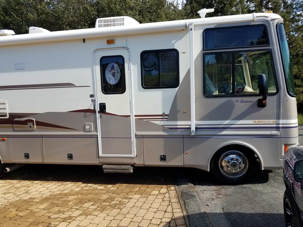 a large white rv is parked on the side of the road