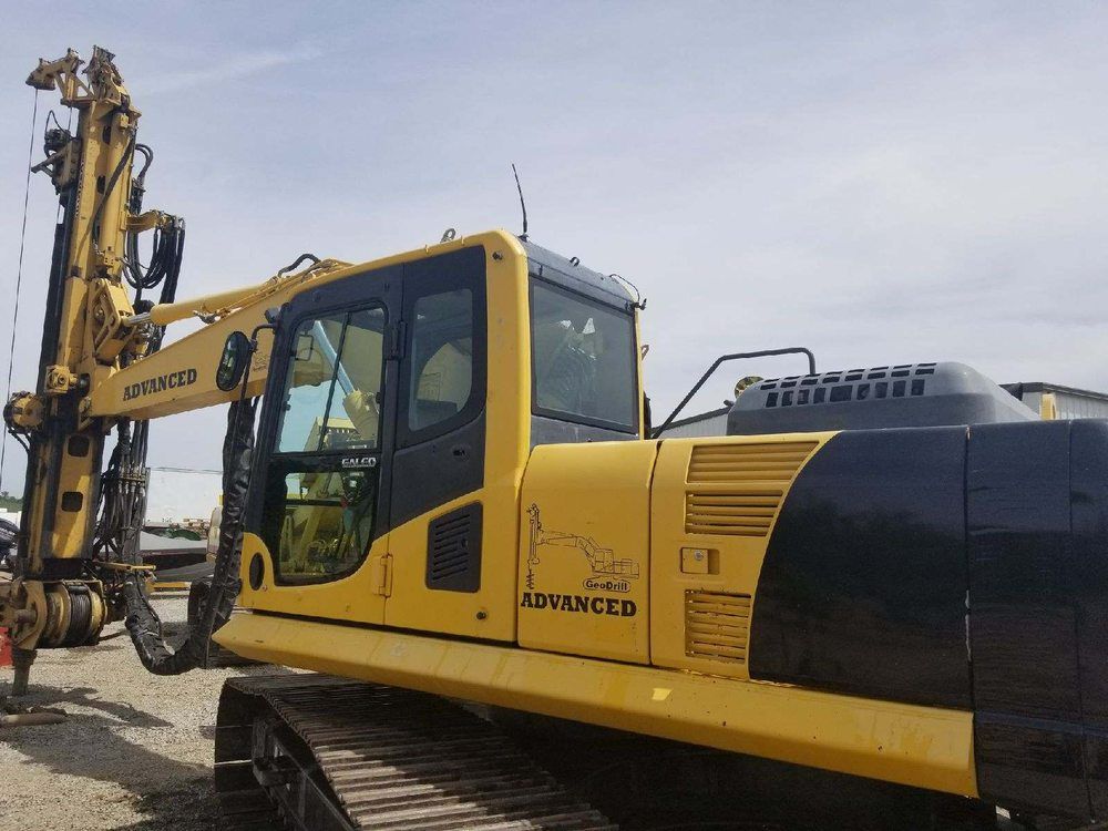 a yellow and black excavator is parked in a dirt lot