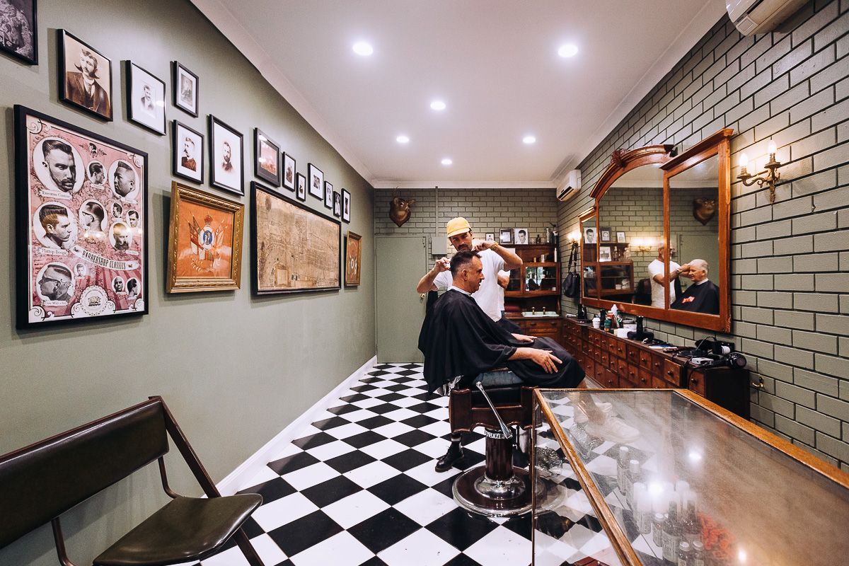 A man is getting his hair cut in a barber shop.