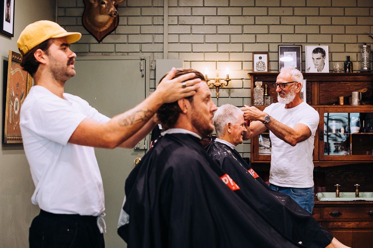 A man is getting his hair cut by a barber in a barber shop.