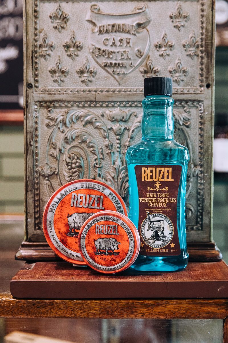 A bottle of reuzel hair products is sitting on a wooden table.