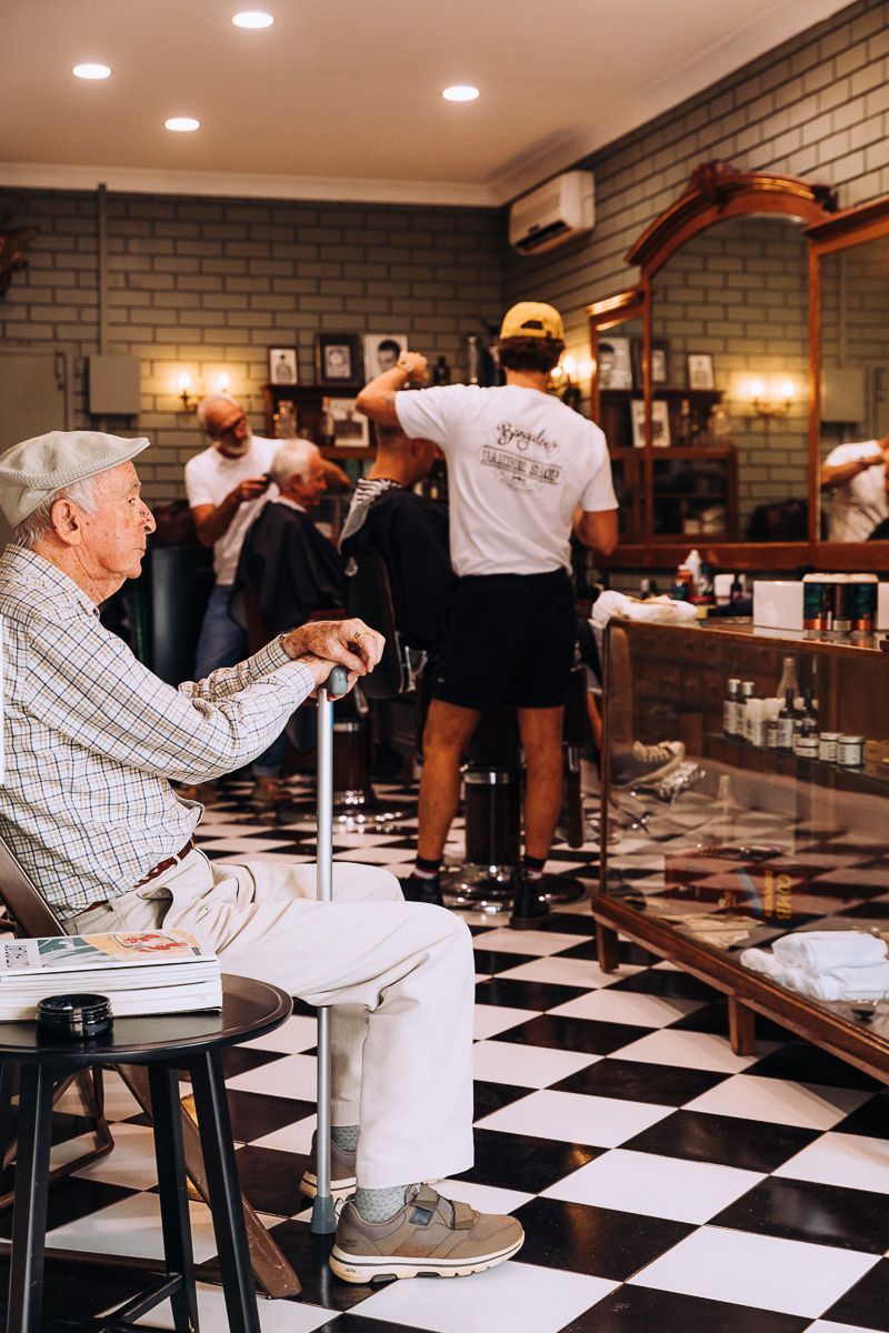 An elderly man is getting his hair cut in a barber shop.