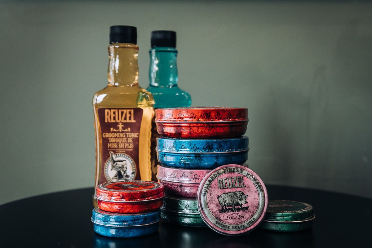 A bottle of reuzel shampoo and a bottle of reuzel pomade are sitting on a table.
