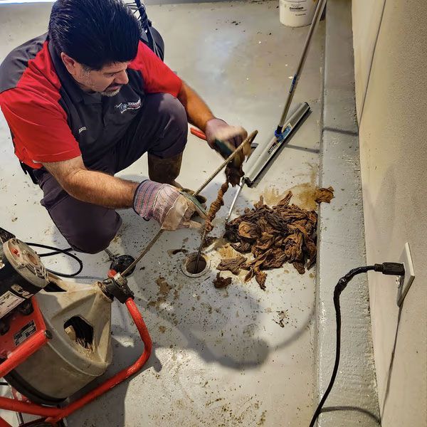 A man in a red shirt is working on a drain