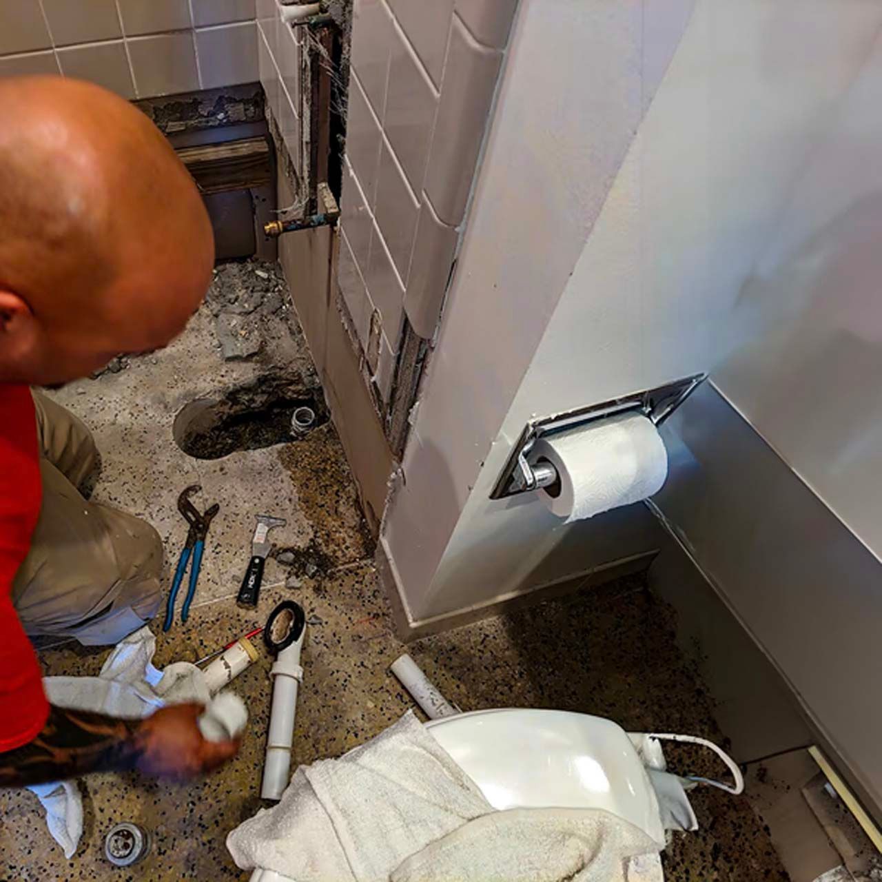A man is working on a toilet in a bathroom