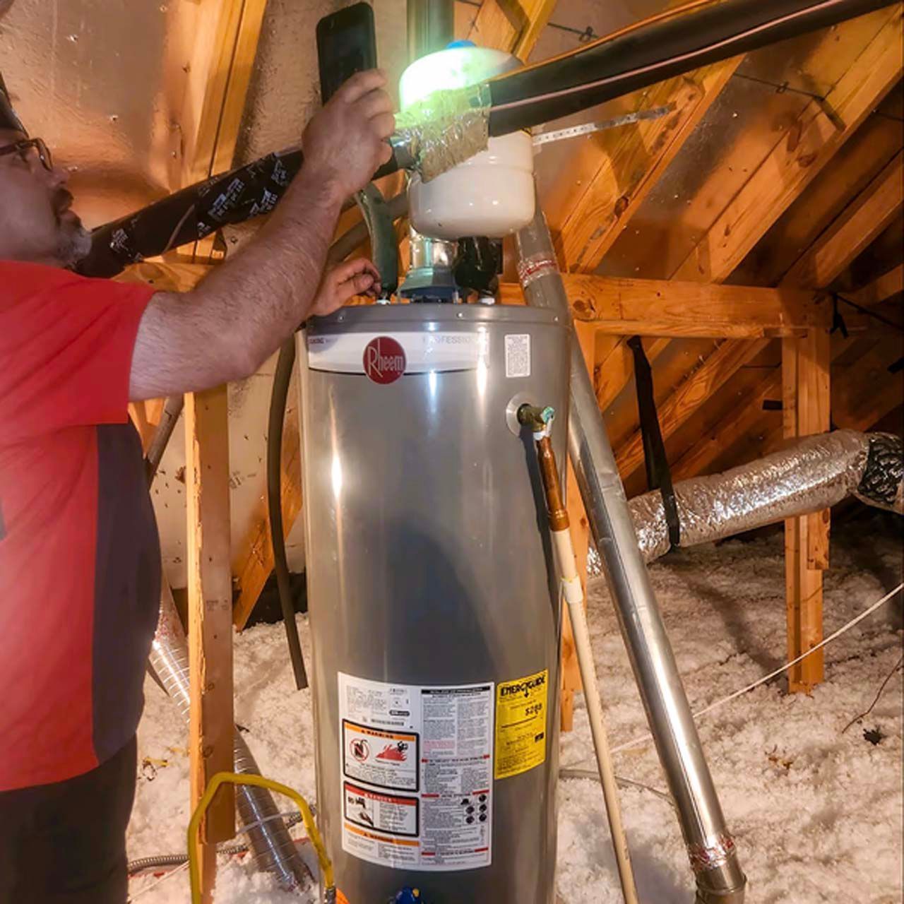 A man in a red shirt is working on a water heater