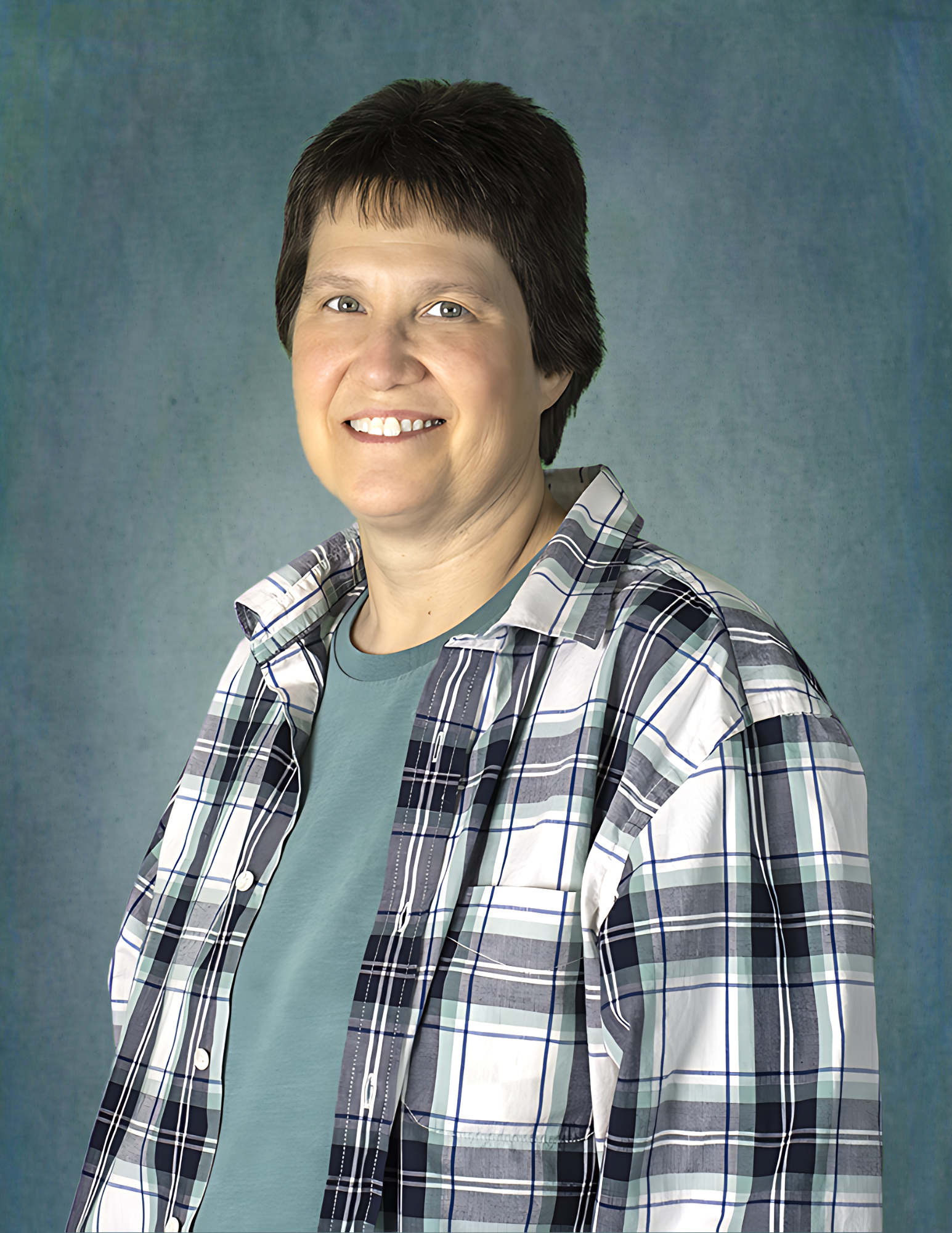 A woman wearing a plaid shirt is smiling for the camera