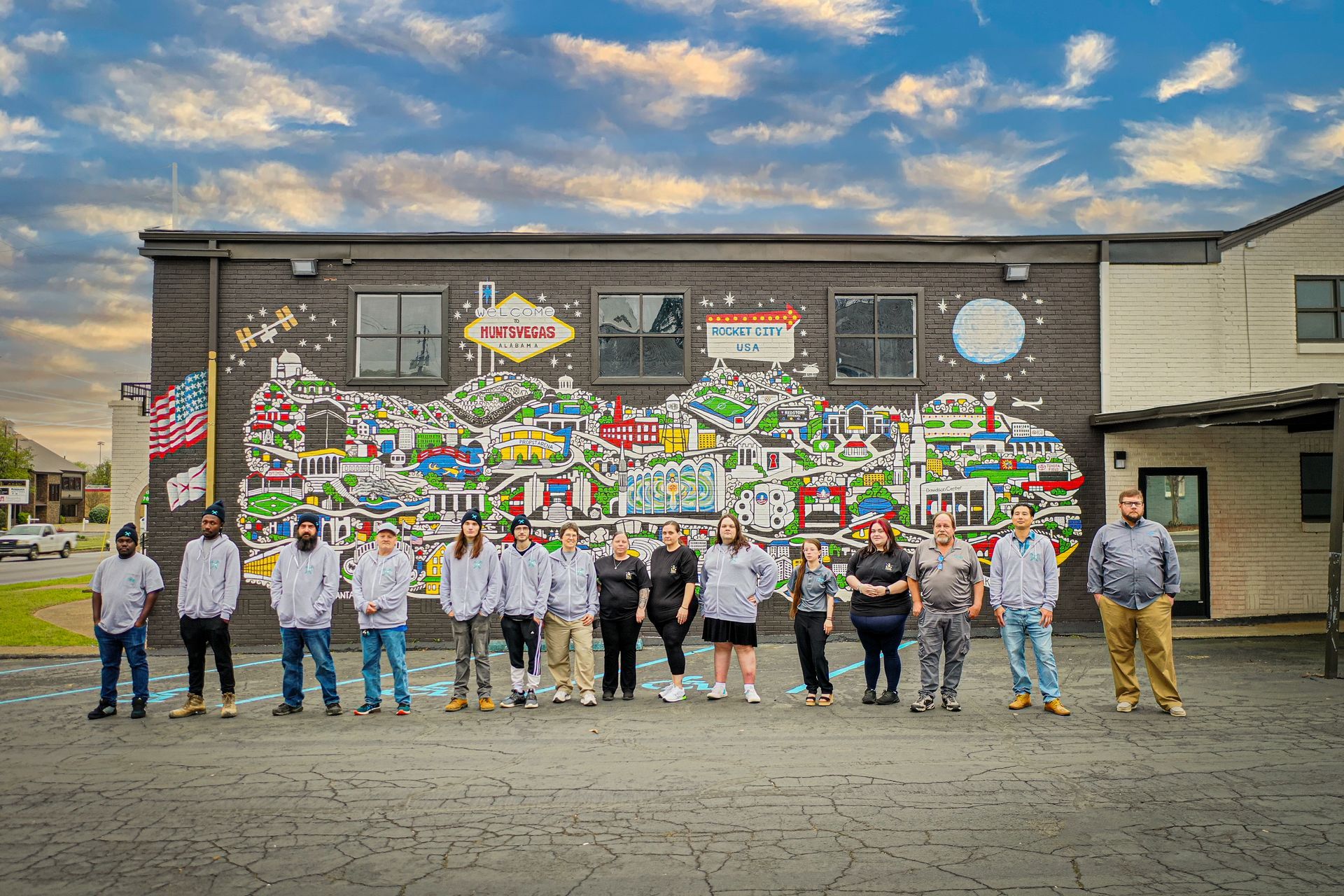 A group of people are standing in front of a large mural on the side of a building.