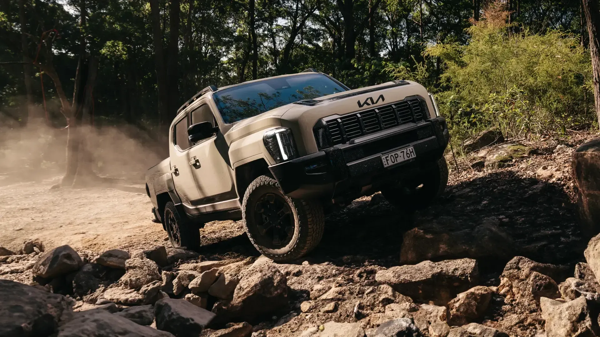 A jeep is driving down a dirt road in the woods.