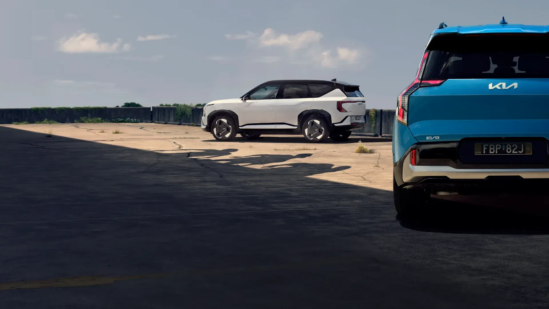 Two cars are parked next to each other on a dirt road.