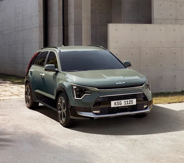 A green car is parked in front of a building.