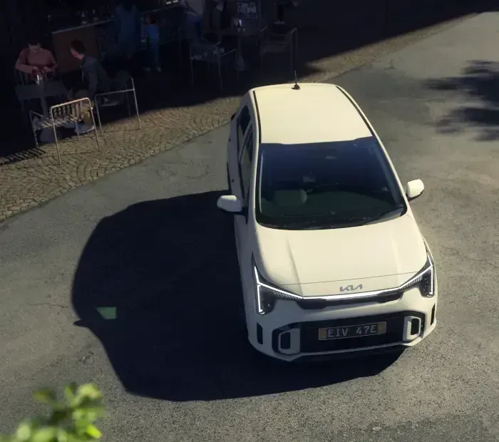 A white car is parked on a sidewalk in front of a building.