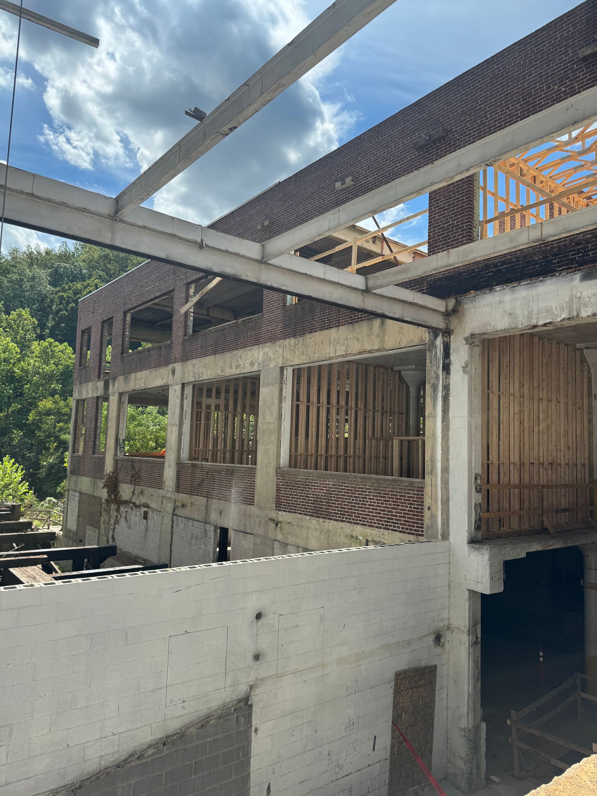 Partially built concrete and wood building with exposed beams under a blue sky