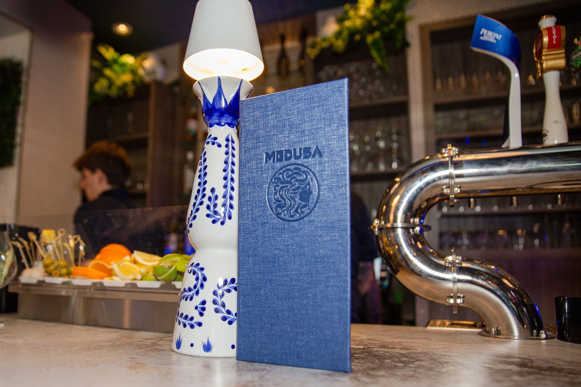 A blue book is sitting on a counter next to a lamp.