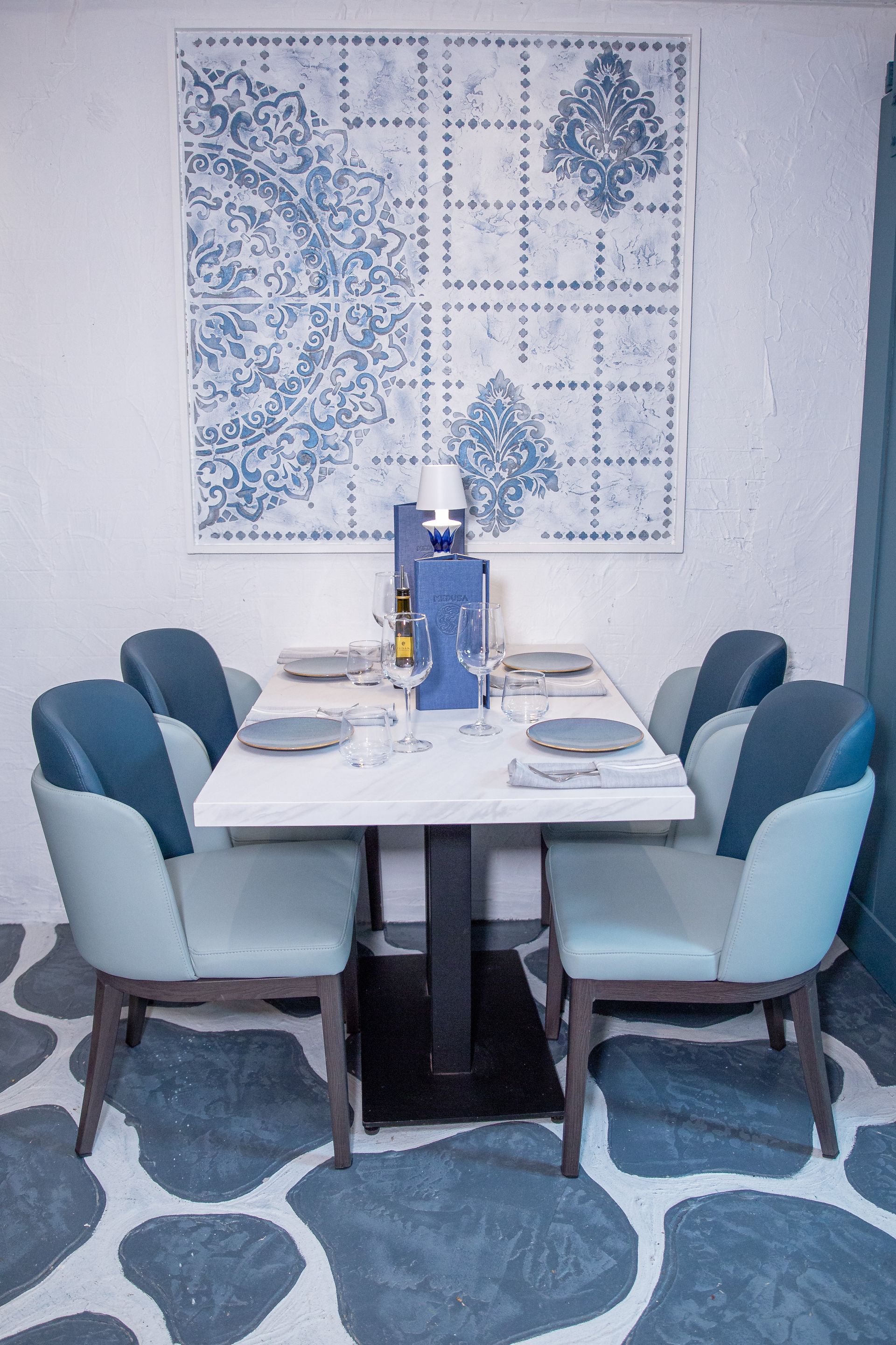 A dining room with a table and chairs and a painting on the wall.