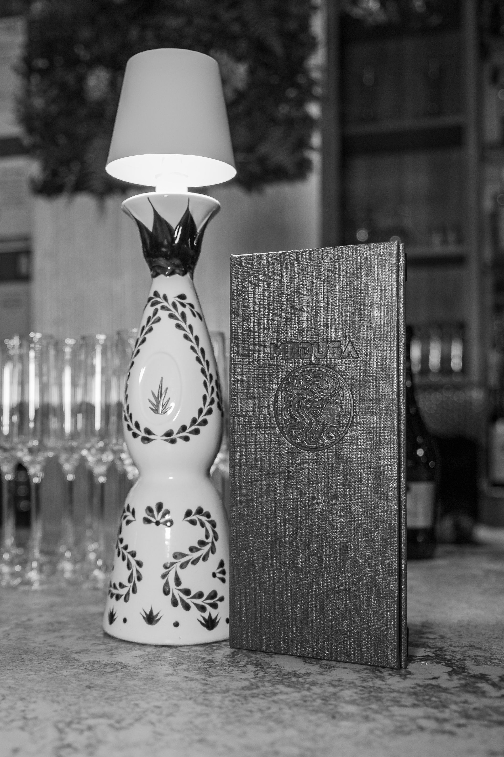 A black and white photo of a lamp and a book on a table.